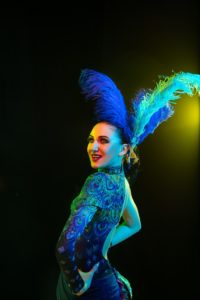 Beautiful young woman in carnival and masquerade costume in colorful neon lights on black background